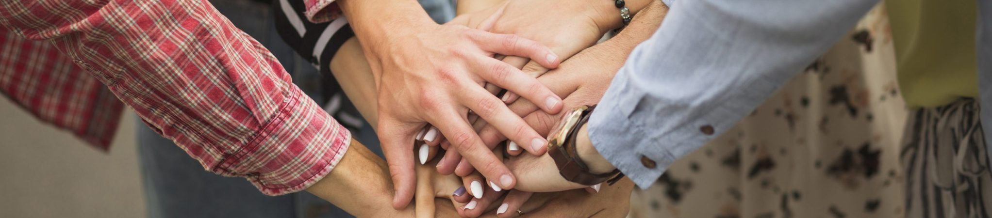 close-up-friends-putting-hands-top-each-other